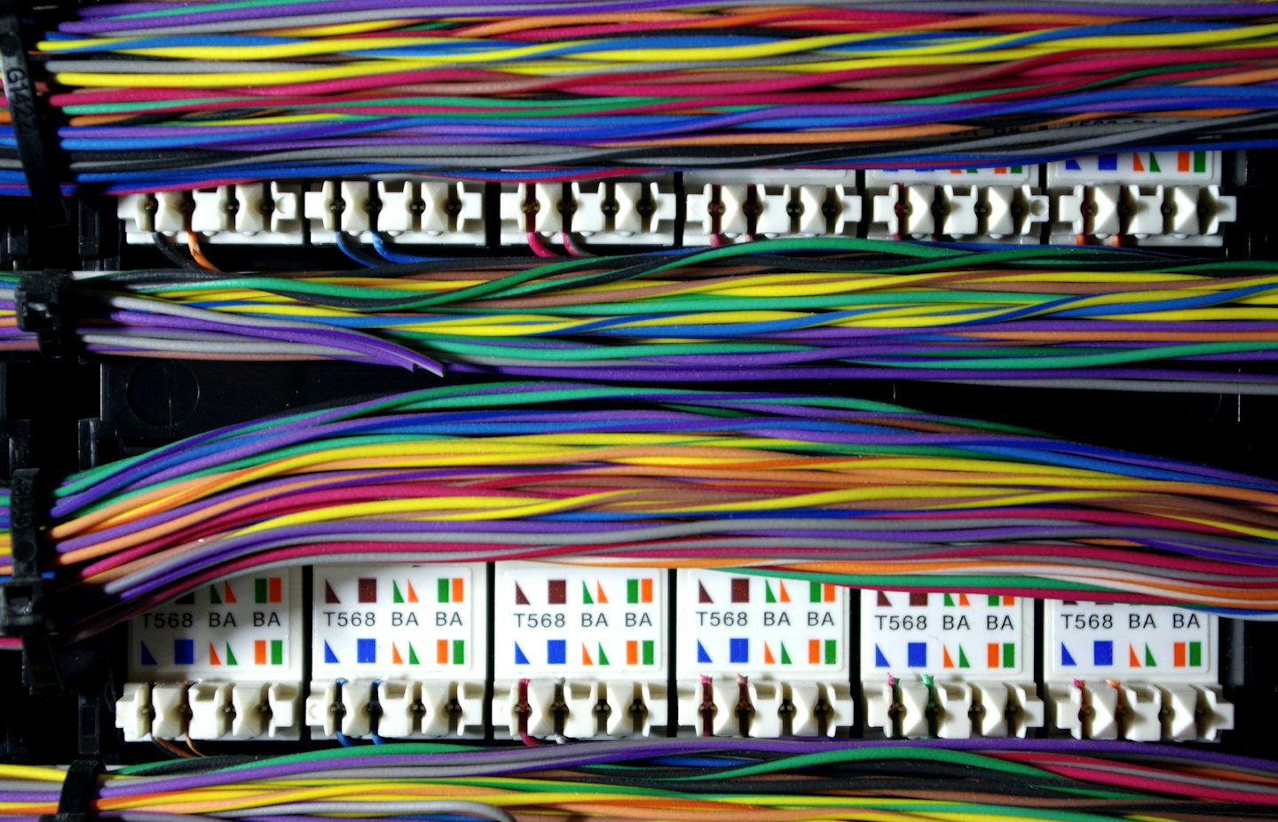Neatly bundled colorful network cables connected to a patch panel.
